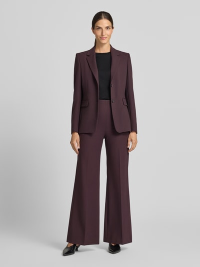 Frauenmodel trägt Flared Fit Hose mit Viskose-Anteil von windsor., dunkel lila Farbton, elastischer Bund, Bügelfalten, glatte Textur, Ganzkörperansicht von vorne.