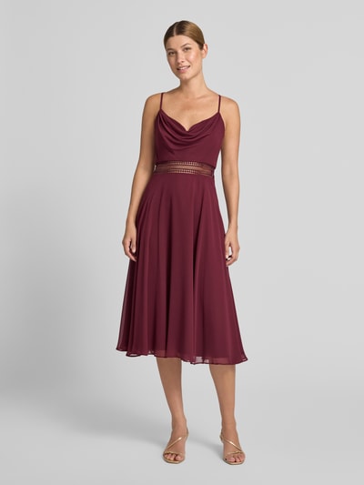 Kobieta nosi sukienkę koktajlową 'Knielanges Cocktailkleid mit Wasserfall-Ausschnitt' od Vera Mont, szyfon, taliowany krój, długość do kolan, lejący dekolt, tasiemka w talii z szydełkowej koronki, długość tyłu w rozmiarze 36: 88 cm, szerokość klatki piersiowej w rozmiarze 36: 33 cm, kolor bordowy, gładka faktura, widok całej sylwetki z przodu.