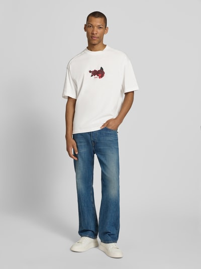 Männermodel trägt Oversized T-Shirt aus reiner Baumwolle Modell 'DOMANS' von HUGO, unifarben mit Label Stitching und Foto-Print, Nahaufnahme Ganzkörperansicht von vorne.
