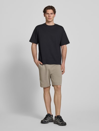 Männermodel trägt Sweatshorts mit elastischem Bund von G-Star Raw im Regular-Fit aus Baumwoll-Mix, Beige, Ganzkörperansicht von vorne. Bundweite in Größe M: 43 cm, Innenbeinlänge: 18 cm.