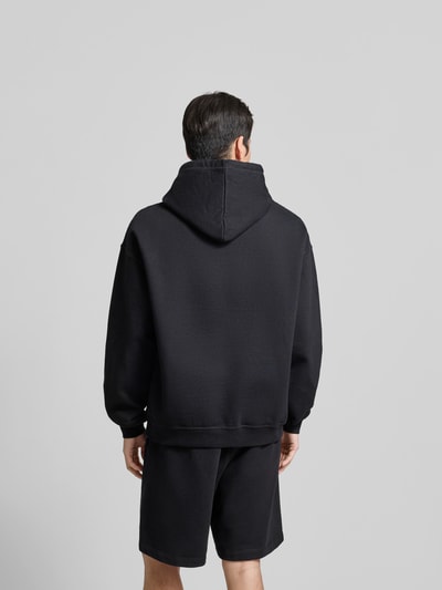 Männermodel trägt Regular Fit Hoodie mit Logo-Stitching von Dsquared2 in Schwarz, reine Baumwolle, Rückansicht, Ganzkörperansicht.