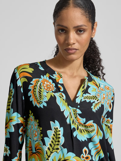 Vrouwenmodel draagt Regular Fit Bluse aus Seide-Elasthan-Mix van HERZENS, kleurrijk allover motief, tuniekkraag, zijaanzicht buste close-up.