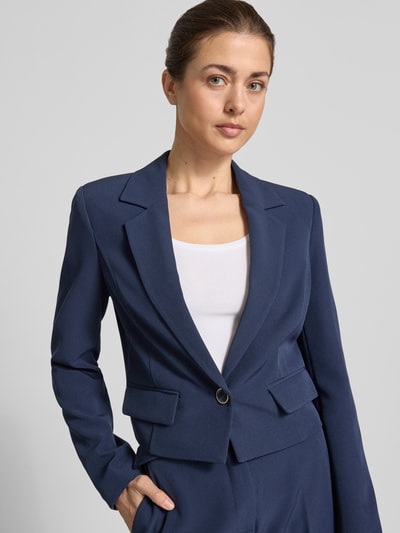 Frauenmodel trägt Cropped Blazer mit Reverskragen Modell 'Leila' von Guess, Elastischer-Material-Mix, Pattentaschen, Knopfverschluss, Ganzkörperansicht von vorne.