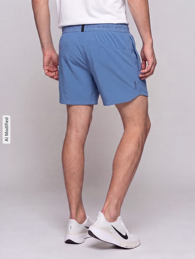 Männermodel trägt Regular Fit Sportshorts mit Dri-FIT-Technologie von Nike in Hellblau, glatte Textur, Herren Sportshorts, Ganzkörperansicht Rückansicht, KI-modifiziertes Bild