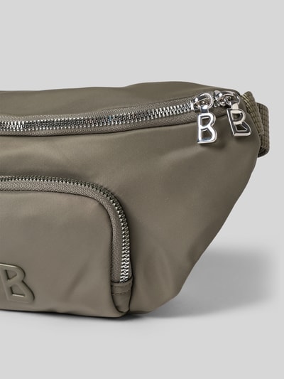 Produktfoto, Handtasche mit Label-Detail Modell 'verbier play 1.0 janica' von BOGNER in Olivgrün, metallene Reißverschlüsse, glatte Textur, rechteckige Form, Vorderseite mit kleinem Fach und Label, verstellbarer Schulterriemen, Maße laut Kontext