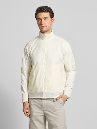 Männermodel trägt Jacke mit Stehkragen und Logo von Salomon in Creme, glatte Oberfläche, Regular Fit, Ganzkörperansicht von vorne. Rückenlänge 70 cm, Schulterbreite 52 cm, Brustweite 61 cm, Ärmellänge 66 cm.