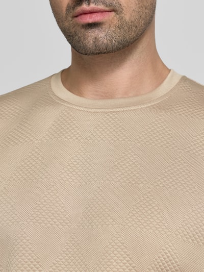 Männermodel trägt Sweatshirt im Allover-Look mit Rundhalsausschnitt von GUESS, beige, strukturierte Dreiecke, reine Baumwolle, Nahaufnahme Oberkörper