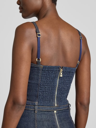 Frauenmodel trägt Jeanstop mit Spaghettiträgern Modell 'ZELDA' von GUESS, dunkelblauer Baumwoll-Elasthan-Mix, sichtbare Struktur, Detailaufnahme Rückansicht.