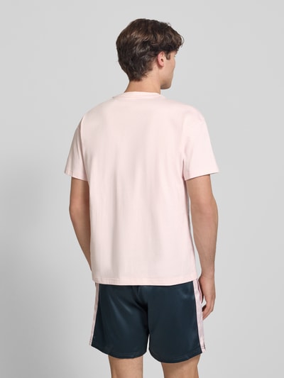 Mężczyznę model nosi T-Shirt mit Label-Print und Rundhalsausschnitt od BLKVIS, bawełna, krój regular fit, długość tyłu w rozmiarze M: 68 cm, widok całej sylwetki z tyłu