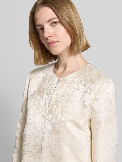 Frauenmodel trägt Blazer mit Hakenverschluss Modell 'FULL' von EMME, cremefarben mit floralem Muster, Nahaufnahme Oberkörper.