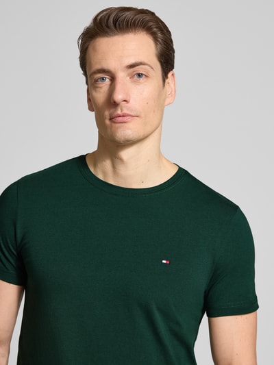 Męski model nosi Slim Fit T-Shirt aus Baumwoll-Mix od Tommy Hilfiger, efekt: jednolity kolor, detal z logo, okrągły dekolt, krótki rękaw, mieszanka bawełny, nahaufnahme oberkörper