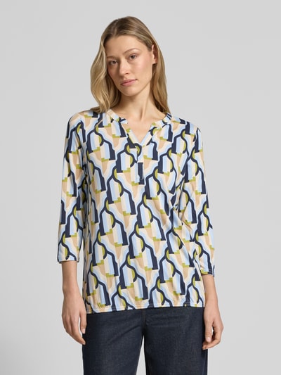 Vrouwenmodel draagt t-shirt met 3/4-mouw model 'FELICITY' van Soyaconcept, katoen- en viscosemix, regular fit, v-hals, ruglengte maat S 63 cm, kleurig geometrisch patroon, vooraanzicht, close-up bovenlichaam.