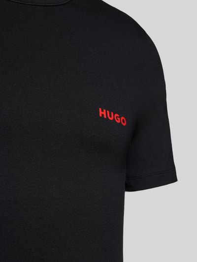 Männermodel trägt T-Shirt mit Label-Print im 3er-Pack von HUGO in Schwarz, reine Baumwolle, Unifarbenes-Design, Nahaufnahme Oberkörper.