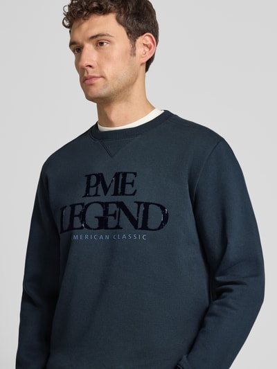Männermodel trägt Sweatshirt mit Label-Print von PME Legend aus Baumwoll-Mix, Regular-Fit, dunkle Farbe, Rundhalsausschnitt, Nahaufnahme Oberkörper.