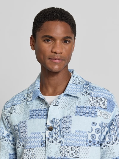 Męski model nosi Regular Fit Overshirt im Allover-Look od Les Deux, bawełniany miks, krój regular fit, jasnoniebieski z patchworkowym wzorem, koszulowy kołnierz, zapięcie na guziki, widoczne faktury; zbliżenie górnej części ciała, widok z przodu.