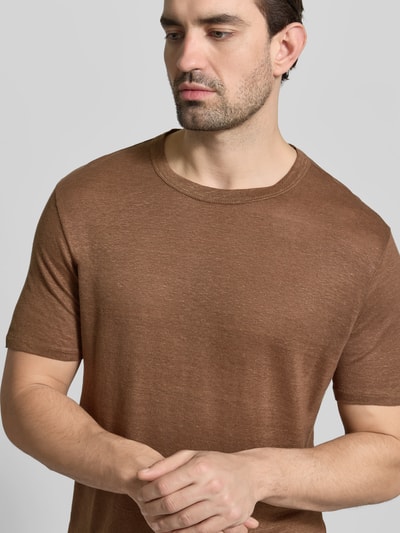 Männermodel trägt Regular Fit T-Shirt aus reinen Leinen von Officine Générale in Braun mit Rundhalsausschnitt, semitransparent, kurzärmelig, Nahaufnahme Oberkörper. Rückenlänge bei Größe M: 68 cm.