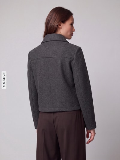 Frauenmodel trägt Regular Fit Blouson mit Umlegekragen Modell 'SAFIR' von VERO MODA in Dunkelgrau, glatte Textur, Ganzkörperansicht Rückansicht, Damen Bomberjacke / Blouson, KI-modifiziertes Bild.