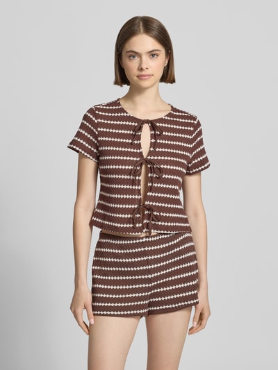 Kobiece modelka nosi Regular Fit Strick-Shirt mit Baumwoll-Anteil Modell 'EVA' von Only, efekt: wzór na całej powierzchni, okrągły dekolt, krótki rękaw, wiązanie, wykończenie materiału: dzianina; Ganzkörperansicht von vorne.