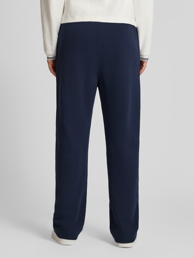 Männermodel trägt Sweatpants mit Längsnähten und wyhaftowane logo von CHAMPION, mieszanka bawełny, krój relaxed fit, pas elastyczny, długość wewnętrzna nogawki w rozmiarze M: 81 cm, kolor granatowy, gładka tekstura, ganzkörperansicht rückansicht.