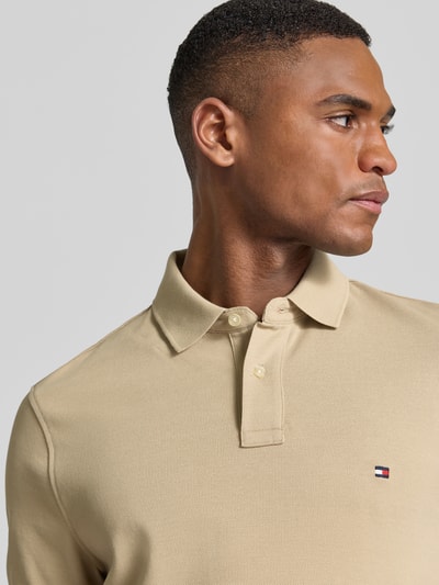 Männermodel trägt Regular Fit Poloshirt aus Baumwoll-Mix von Tommy Hilfiger, efekt: jednolity kolor, krój regular fit, wyhaftowane logo, kołnierzyk polo, zapięcie na 2 guziki, krótki rękaw, wykończenie: z rozcięciem, wykończenie materiału: pika, mieszanka bawełny, Nahaufnahme górnej części ciała.