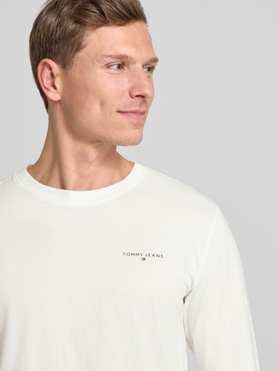 Männermodel trägt Slim Fit Langarmshirt aus reine Baumwolle von Tommy Jeans, Optik: Unifarben, Label-Schriftzug, Nahaufnahme Oberkörper