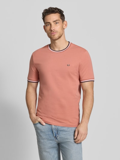 Mężczyznamodel nosi T-Shirt mit Kontraststreifen und Rundhalsausschnitt von Christian Berg Men w kolorze łososiowym, krój regular fit, bawełna z elastanem, długość tyłu w rozmiarze M 71 cm, widok całej sylwetki z przodu.