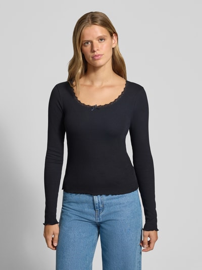 Kobiece modelka nosi Longsleeve mit Spitzenbesatz und Rundhalsausschnitt von REVIEW, Mieszanka bawełny i elastanu, krój slim fit, Efekt prążkowania, obszycie koronką, okrągły dekolt, Długość tyłu w rozmiarze S: 50 cm, kolor czarny, jednolity, gładka tekstura, Ganzkörperansicht von vorne.