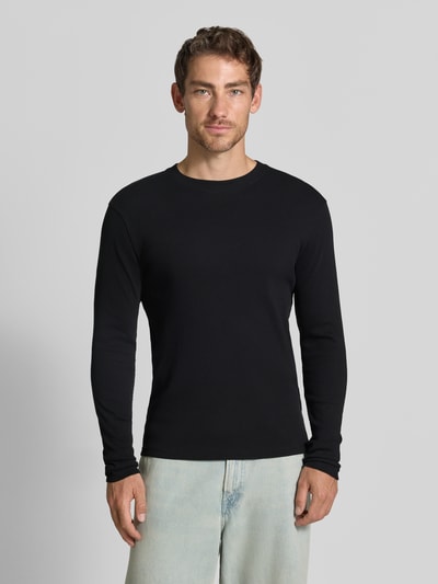 Męski model nosi bluzkę z długim rękawem Slim Fit Longsleeve aus reiner Baumwolle Model 'Enil' von DRYKORN, krój slim fit, bawełna, fakturowany wzór, okrągły dekolt, długość tyłu 67 cm, długość rękawów 69 cm, widok całej sylwetki z przodu.