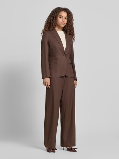 Vrouwenmodel draagt Blazer met Reverskraag en Pattentaschen van Jake*s collectie in bruin, getailleerd model, knoopsluiting, klepzakken, ruglengte maat 38: 65 cm, borstwijdte maat 38: 46 cm, mouwlengte maat 38: 62 cm, effen structuur, geheel vooraanzicht.