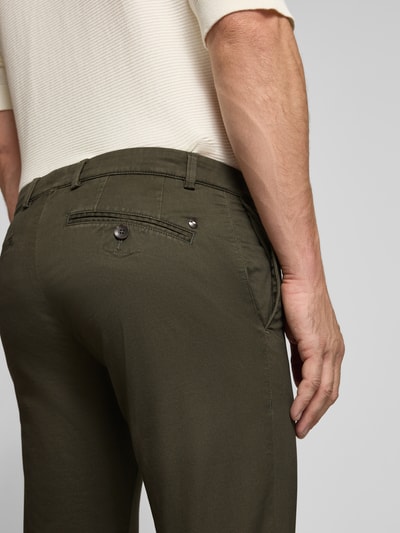 Männermodel trägt Slim Fit Chino aus Baumwoll-Mix von bugatti in Dunkelgrün, Detailaufnahme Rückansicht, Münztasche und Gesäßtaschen sichtbar.