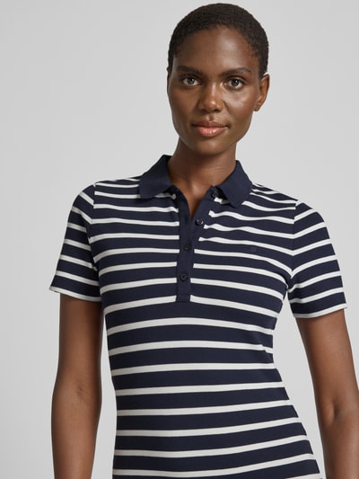 Vrouwenmodel draagt knielanges Polokleid mit kurzer Knopfleiste van Gant, navy-wit gestreept, getailleerde fit, katoenmix, close-up bovenlijf.