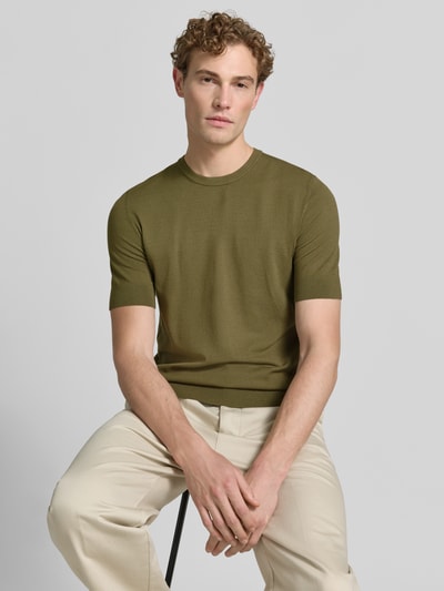 Męski model nosi Slim Fit T-Shirt aus Feinstrick model 'SAN CARL-CV' od HUGO w oliwkowym kolorze, gładka tekstura, zdjęcie w półzbliżeniu przód.