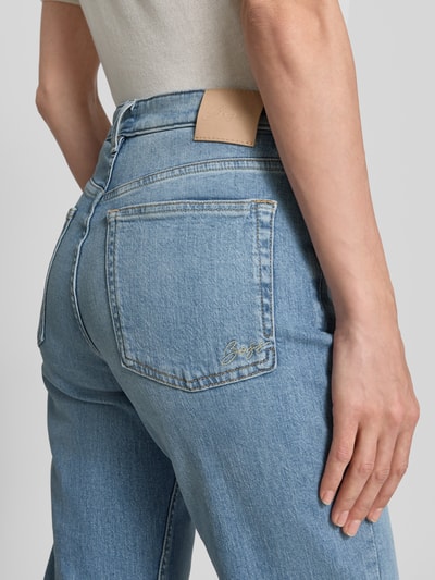 Frauenmodel trägt Cropped Jeans aus Baumwoll-Mix Modell 'C-SOFT KICK FLARE1.0' von BOSS Orange in blauer Denim-Optik mit Label-Patch, Nieten, 5-Pocket-Design, Fransen am Beinabschluss; Material Baumwoll-Mix; Detailaufnahme Rückansicht.