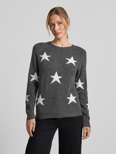 Frauenmodel trägt grauen Regular Fit Pullover mit Rundhalsausschnitt Modell 'DOFFY' von VERO MODA mit weißen Sternen, Ganzkörperansicht von vorne.