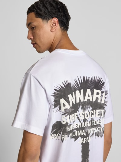 Männermodel trägt Relaxed Fit T-Shirt mit Logo-Print von ANNARR aus Reine Baumwolle, weiß, schwarze Palmen-Grafik, Rückenlänge 72 cm, Ganzkörperansicht Rückansicht.