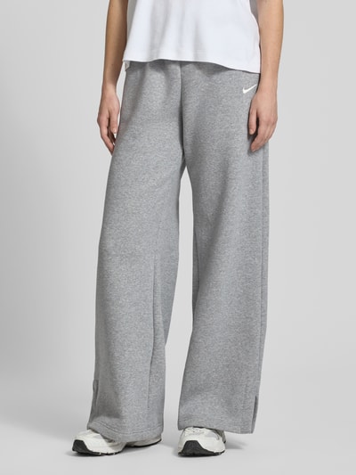 Frauenmodel trägt Loose Fit Sweatpants mit Logo-Stitching Modell 'Phoenix' von Nike aus Baumwoll-Mix in Grau, Nahaufnahme Unterkörper. Innenbeinlänge bei Größe M: 80 cm, Tunnelzug, für Damen.
