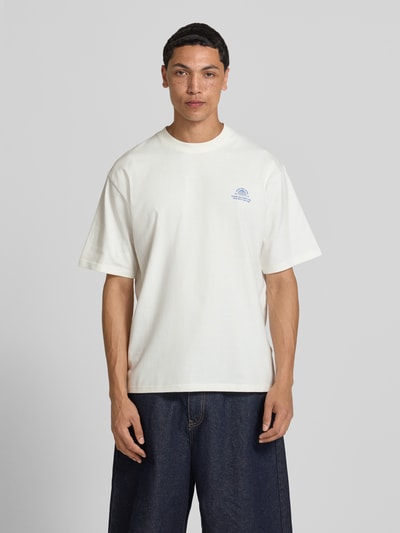 Männermodel trägt T-Shirt mit Statement-Print und Rundhalsausschnitt von Redefined Rebel, Baumwoll-Mix, Relaxed-Fit, Modell Bruno, Ganzkörperansicht von vorne. Rückenlänge bei Größe M 70 cm.