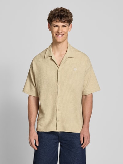 Männermodel trägt Regular Fit Freizeithemd mit Label-Patch Modell 'LIBCO' von Pegador, Reverskragen, Material-Mix, Knopfleiste, kurzärmelig, Beige-Ton, strukturierte Textur, locker fallend, Rückenlänge 72 cm, Schulterbreite 41 cm, Ärmellänge 35 cm, Ganzkörperansicht von vorne.
