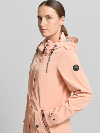 Vrouwenmodel draagt peachkleurige damesjack met capuchon, tunnelkoord, ritszakken, mouwsluitingen, model 'GS94' van G.I.G.A. DX, regular fit. Nahaufnahme Oberkörper.