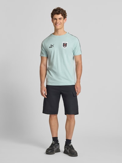 Männermodel trägt Herren T-Shirt mit Rundhalsausschnitt Modell 'ÖFB KING' von PUMA PERFORMANCE in Mint, Regular-Fit, Reine Baumwolle, Ganzkörperansicht von vorne.
