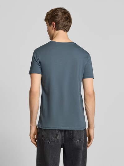 Męski model nosi T-Shirt mit Label-Details Modell 'BASIC' von Alpha Industries z czystej bawełny, prosty krój, okrągły dekolt, długość tyłu 67 cm w rozmiarze M, widok całej sylwetki od tyłu.