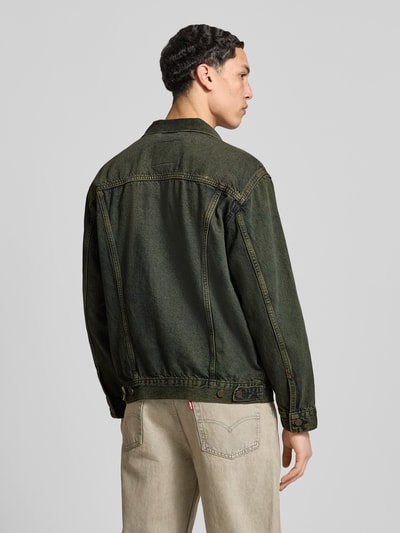 Männermodel trägt Relaxed Fit Jeansjacke aus reiner Baumwolle Modell 'TRUCKER' von Levi's® in grünem Used Look, Ganzkörperansicht Rückansicht.