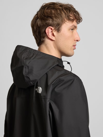 Męski model nosi Kurtkę z logo model 'ANTORA' od The North Face w kolorze czarnym, kaptur z tunelem, zamek błyskawiczny, krój regular fit, detal logo, szczegóły: długość tyłu w rozmiarze M 74 cm, szerokość ramion w rozmiarze M 46 cm, szerokość klatki piersiowej w rozmiarze M 58 cm, długość rękawów w rozmiarze M 69 cm, detaliczny, matowy materiał, detal logo na plecach, zdjęcie: ujęcie od tyłu, zbliżenie na górną część pleców.