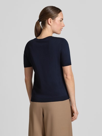 Vrouwenmodel draagt Regular fit gebreid shirt uit mix van zijde en katoen Model 'WKDAGRO' van Weekend Max Mara, effen fijngebreid design, met korte mouwen, ronde hals, geribde mouw- en rompzoom, ganse lichaamsweergave achteraan.