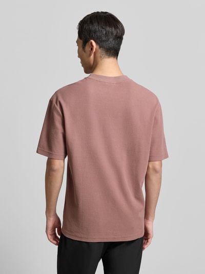 Männermodel trägt Regular Fit T-Shirt aus reiner Baumwolle Modell 'DAFFL' von HUGO in Altrosa, strukturierte Jacquard-Optik, Ganzkörperansicht Rückansicht.