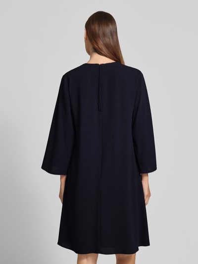 Männermodel trägt Knielanges Kleid mit V-Ausschnitt von Windsor, Linia A, długość do kolan, dekolt w serek, frędzle, fließender Stoff, długość tyłu w rozmiarze 36: 98 cm, szerokość w rozmiarze 36: 46 cm, długość rękawów w rozmiarze 36: 55 cm, ciemny kolor, gładka tekstura, Ganzkörperansicht Rückansicht.