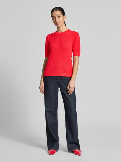 Frauenmodel trägt Slim Fit Damen T-Shirt in Strick-Optik Modell 'Vidalo' von Vila, rote Farbe, reine Baumwolle, Rundhalsausschnitt, Ganzkörperansicht von vorne.