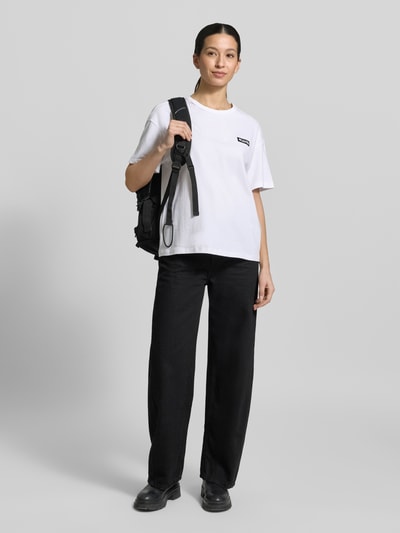 Kobiece model nosi T-shirt aus reiner Baumwolle mit Modell 'CSC™' von Columbia w białym kolorze, luźny krój, okrągły dekolt, nadruk z logo, krótki rękaw, technologia Omni-Shade UPF 30, długość tyłu 60 cm w rozmiarze S, widok całej sylwetki z przodu.