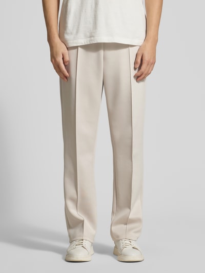 Mężczyzna nosi Track Pants mit Eingrifftaschen Modell 'Ballier' od Les Deux w kolorze jasnym, materiał elastyczny, proste nogawki, widok z przodu, zbliżenie na dolną część ciała.