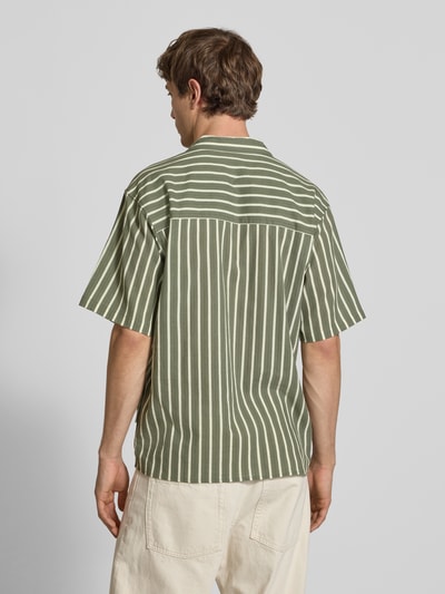 Männermodel trägt Regular Fit Freizeithemd mit Reverskragen Modell 'HOWIE' von Redefined Rebel, Reine Baumwolle, Allover-Look, Label-Detail, Ganzkörperansicht Rückansicht. Rückenlänge bei Größe M 60 cm, Schulterbreite 60 cm, Ärmellänge 30 cm. Beige Hose, grün-weiß gestreiftes Hemd, glatte Textur.